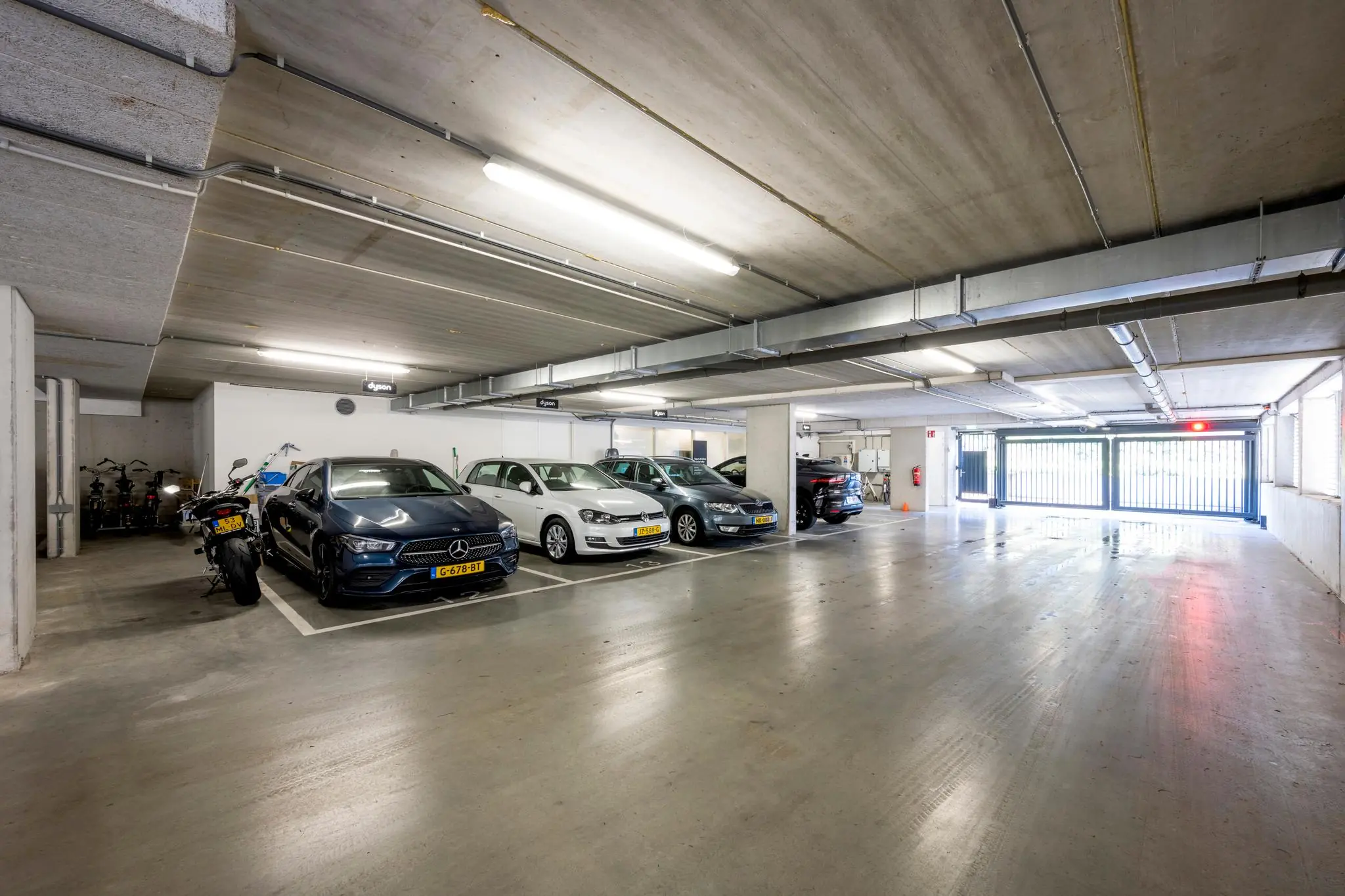 Ondergrondse parkeergarage aan de Fred. Roeskestraat met geparkeerde auto’s, motoren en een gesloten hek met rood licht.